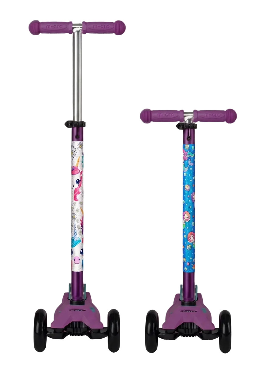 Two children's kick scooters shown side by side against a solid gray background. The scooter on the left has a white handlebar stem decorated with pink flamingos, and the scooter on the right has a blue handlebar stem decorated with colorful cartoon characters.